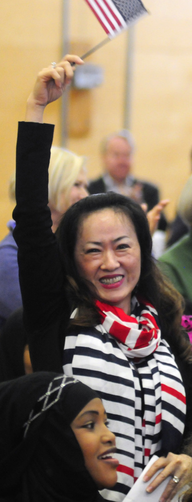 New citizen Chau Do, of Lewiston, waves an American flag after a naturalization ceremony Friday at Maranacook Community Middle School in Readfield.