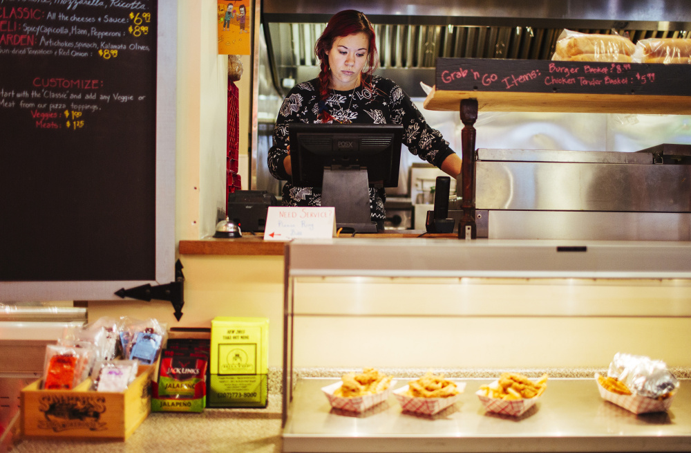 Ambre Davidson works the register at the Hilltop Superette in Portland on Wednesday. She would appreciate an increase to a $12 minimum wage. “I have a 4-year-old, and a couple dollars extra an hour would be a huge thing for me, especially with child care,” she said.