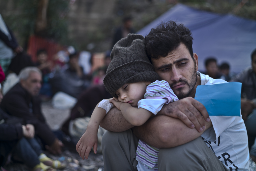 A Syrian refugee holds his sleeping child Oct. 4, after arriving on a dinghy from the Turkish coast to Greece. Despite last week’s tragic events, France is sticking by its pledge to take in 30,000 Syrian refugees – while President Obama’s plan to accept 10,000 is encountering massive resistance in the U.S.