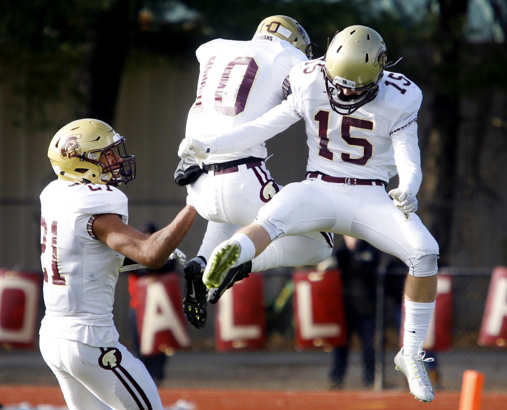 Thornton Academy players Greg Ruff, left, Benjamin Lambert, 10, and Cameron Cadorette celebrate in the second quarter after Lambert intercepted a pass in Saturday’s Class A state football championship at Fitzpatrick Stadium.