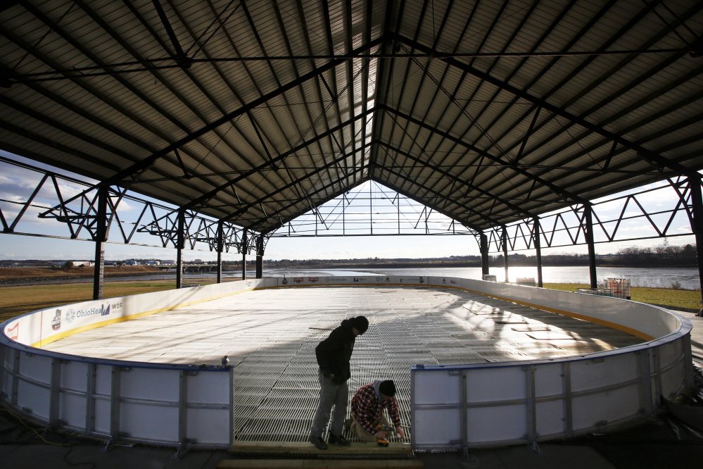 Dennis Patenaude, left, and Joshua Gilliam of Rink Specialists install ice mats Thursday at a new Thompson’s Point rink. The rink opens next Tuesday and will include warming stations, food trucks and a heated lounge.