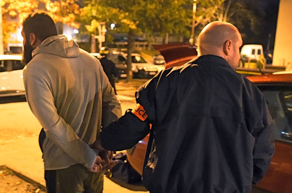 A man is detained by a police officer after a raid in the Mirail district in Toulouse, southwestern France, Monday. The Associated Press 