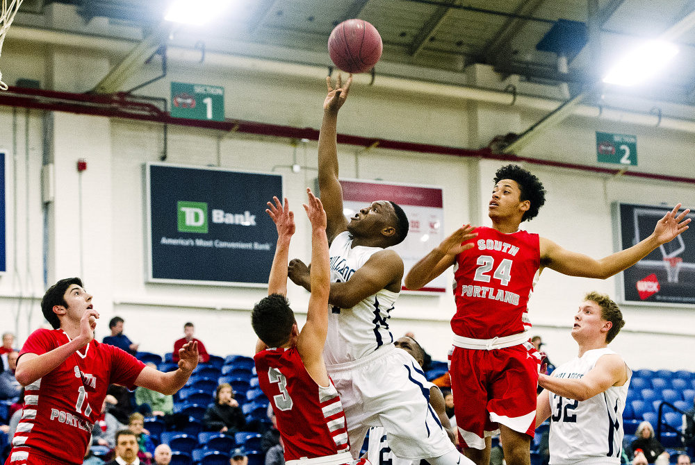 Portland’s Amir Moss drives the lane, splitting South Portland defenders, from left, Matt Pelletier, Sam DePaolo and Ansel Stilley at the Portland Expo Friday. Gabe Souza/Staff Photographer