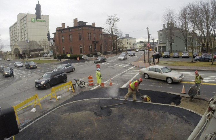 Workers on Friday shave back the sidewalk bump-out on Spring Street in Portland that prompted criticism from some West End residents.