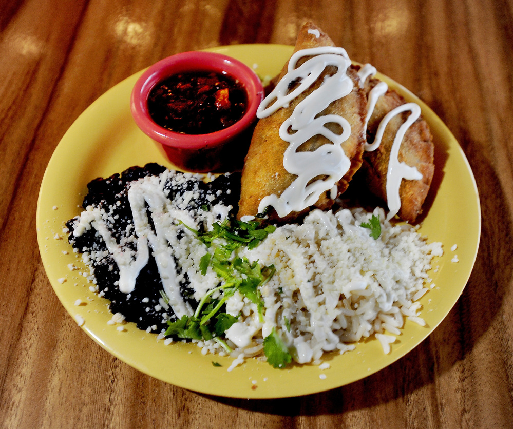 Chicken empanadas with beans, rice and sauce.