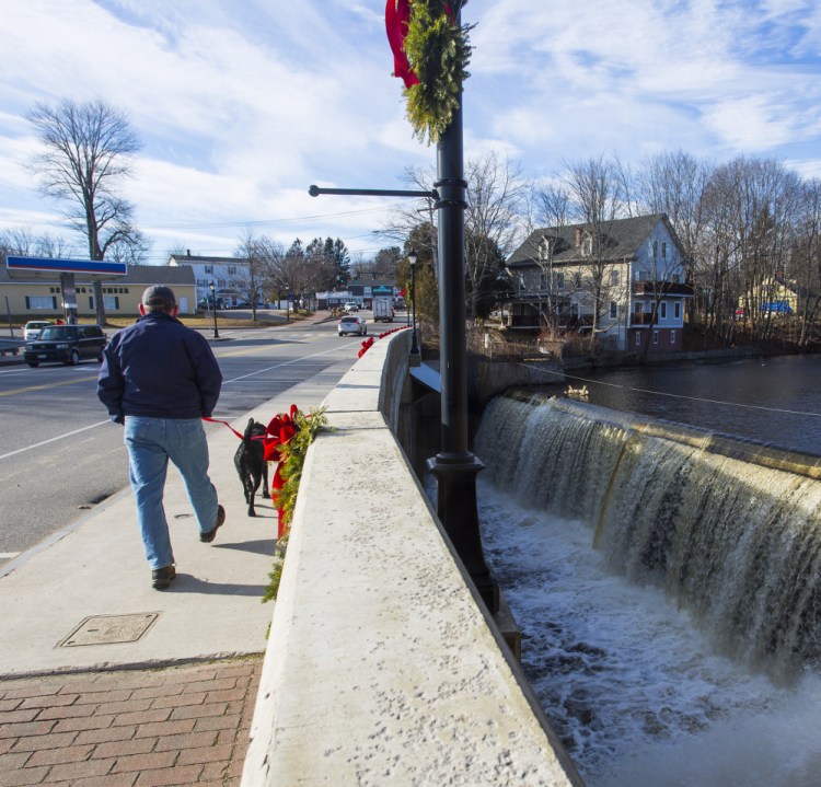 A man and his dog cross over the Mousam River in Kennebunk near the Kesslen Dam, one of three dams being considered for removal.