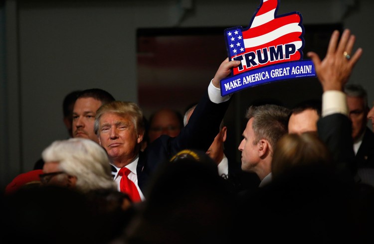 Republican presidential candidate Donald Trump holds one of his signs after a rally coinciding with Pearl Harbor Day at Patriots Point aboard the aircraft carrier USS Yorktown in Mt. Pleasant, S.C., on Monday.