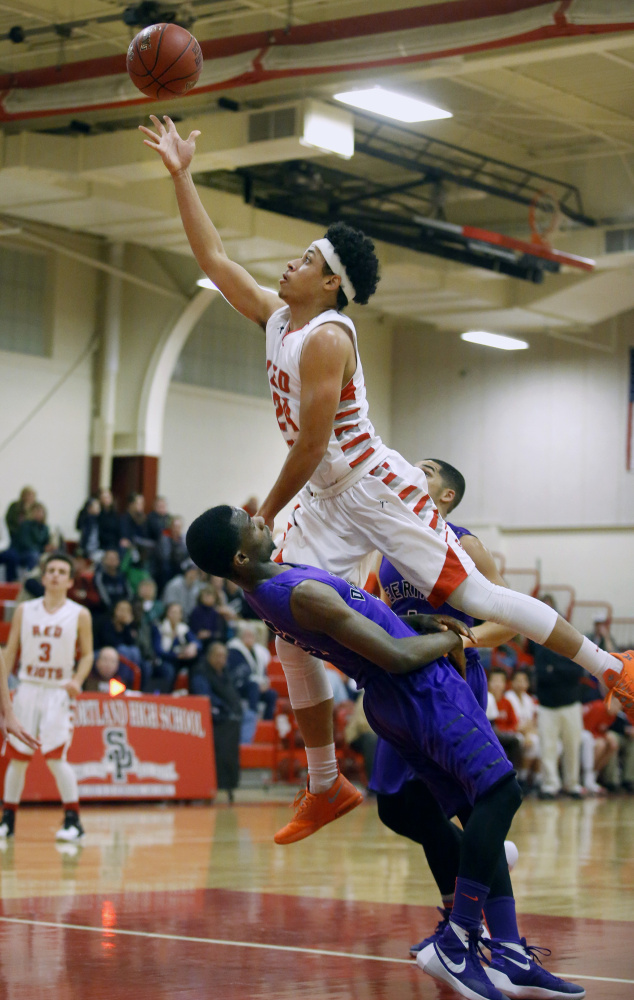 South Portland’s Ansel Stilley avoids a charge and scores over Ben Williams of Deering in the first quarter. Stilley led his team with 10 points, but the Red Riots had a six-game winning streak snapped.