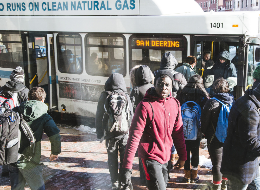 Students join other riders at the Metro bus stop across from the Portland Public Library.  Their numbers have helped push the system’s ridership to its highest since 1986. They accounted for 18 percent of total trips during the last four months of 2015.