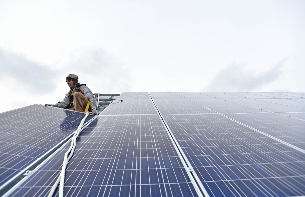 Ben Holt, with Insource Renewables, installs a solar panel Tuesday on the Vassalboro Friends Meeting building in Vassalboro.