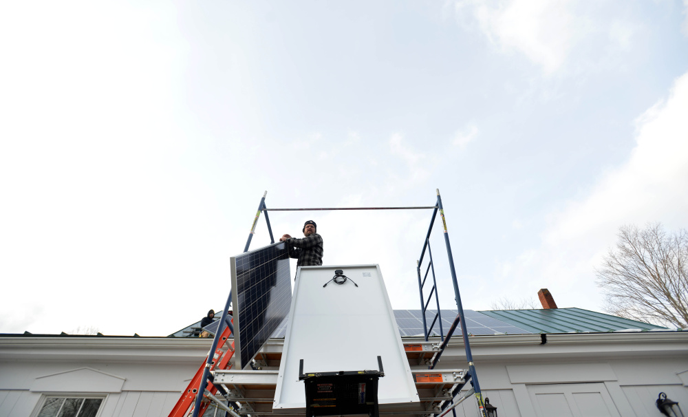 Matt Wagner prepares a solar panel for installation Tuesday on the Vassalboro Friends Meeting building in Vassalboro.