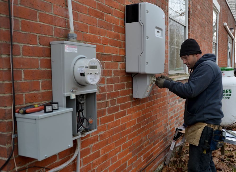 Dave Lawless, an electrician with Insource Renewables, installs a power converter Tuesday to use the solar array on the roof of the Vassalboro Friends Meeting building in Vassalboro.