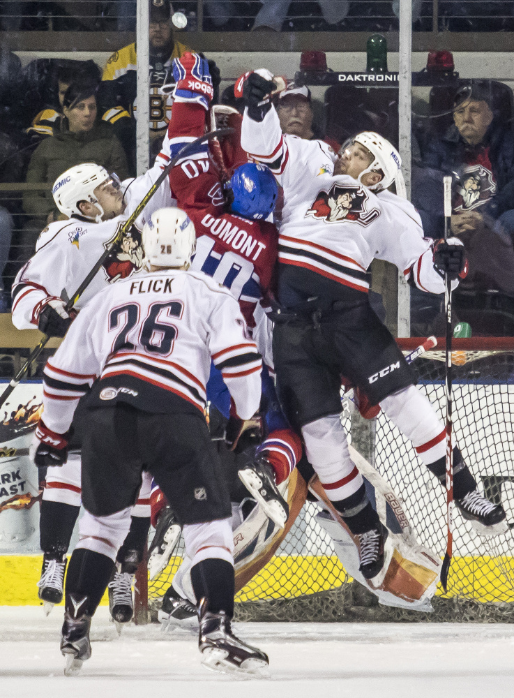 A jump puck? From left, MacKenzie Weegar and Rob Flick of the Pirates battle with Gabriel Dumont of the St. John’s Ice Caps with Cameron Gaunce of the Pirates in on the action in front of the St. John’s goal in the second period of Wednesday’s game at the Cross Insurance Arena .