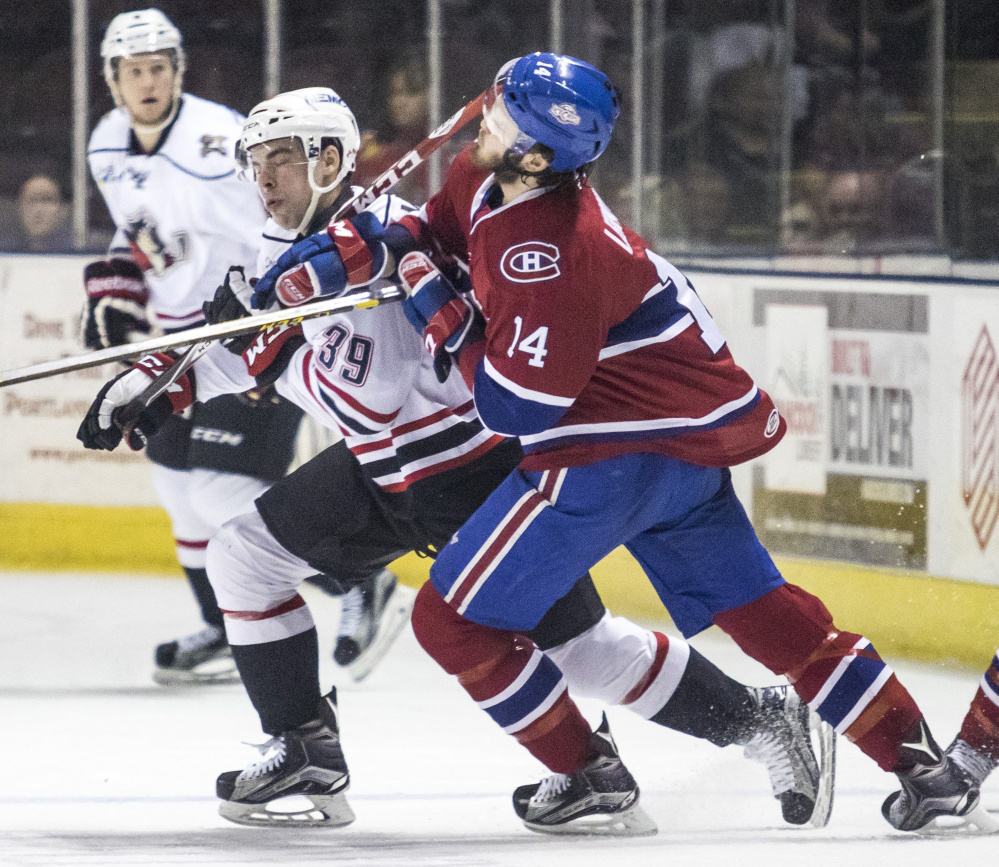 Greg McKegg of the Portland Pirates, at left, gets his stick near the face of St. John’s defenseman Brett Lernout in Wednesday night’s game at Portland. The Pirates won 4-1.