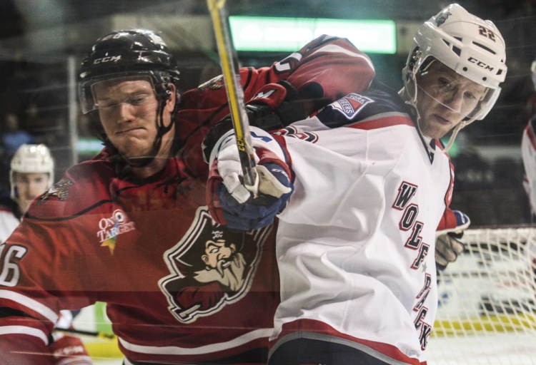 Portland left wing Rob Flick and Hartford’s Mat Bodie push each other near the plexiglass for possession of the puck Friday in Portland.