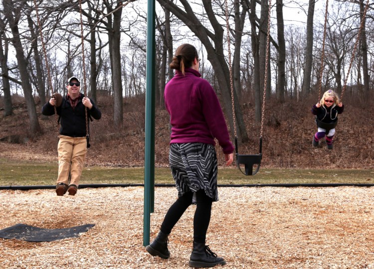 Sarah Hayes watches Matt Warner and Quinn Warner, 2, all of Portland, use the swings while they take advantage of the warm weather at Fort Williams Park in Cape Elizabeth on Wednesday.