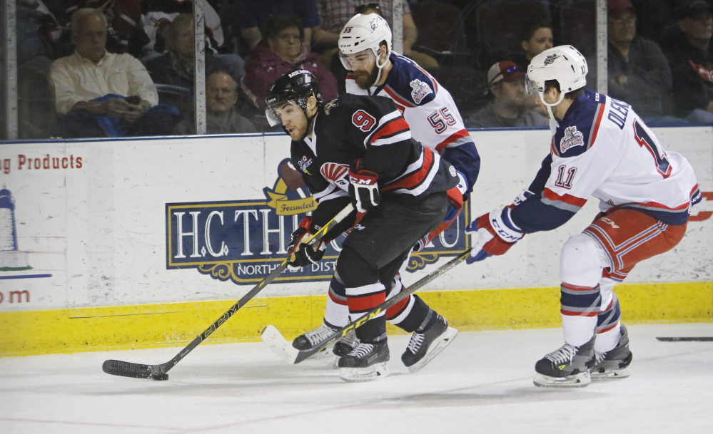 Rocco Grimaldi carries the puck ahead of Chris Summers and Travis Olesuk during first period action at the Cross Insurance Arena in Portland.  Jill Brady/Staff Photographer