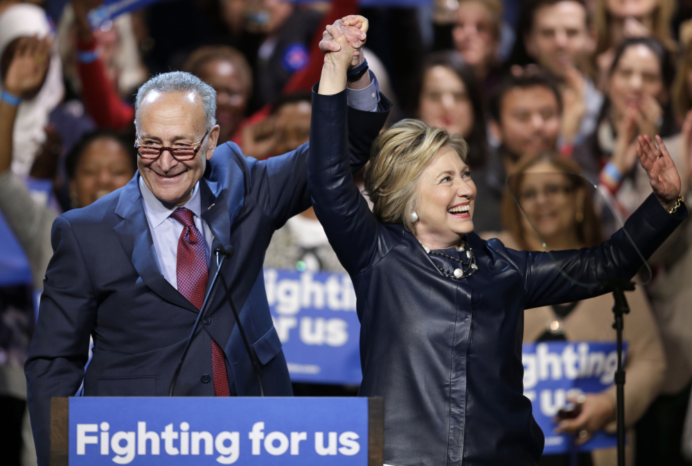 Democratic presidential candidate Hillary Clinton holds up hands with Sen. Charles Schumer, D-N.Y., during a rally at the Apollo Theater in New York on Wednesday. In New York, Clinton highlights her record as senator, particular her economic work upstate and aid to 9/11 first responders.