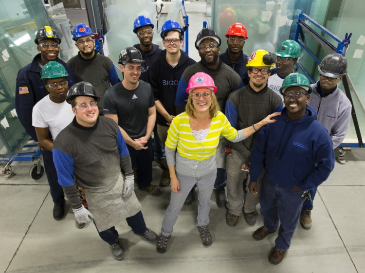 Cindy Caplice, human resources manager at Sigco, stands with employees Wednesday in the Westbrook plant, which recruits asylum-seekers for jobs starting at $13-$15 per hour.