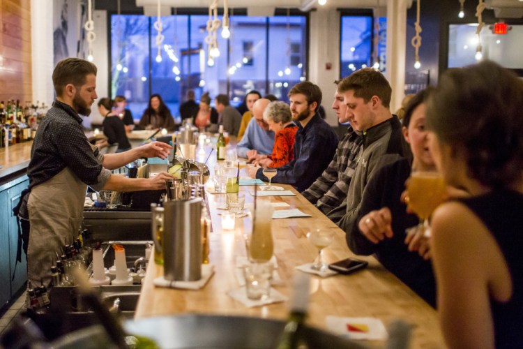 Kit Paschal, co-owner of Roustabout, mixes a drink while chatting with patrons during dinner service.