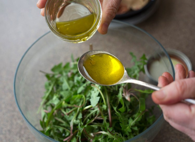 Dressing is poured over the makings for a dandelion greens salad. Derek Davis/Staff Photographer