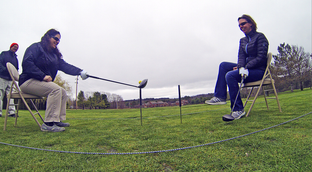 Recreational therapists Liz Marrone, left, and Courtney Oliver take one-handed swings with short clubs while seated to simulate golfing from a wheelchair during training on how to teach adaptive golf on Thursday at the Augusta Country Club in Manchester.