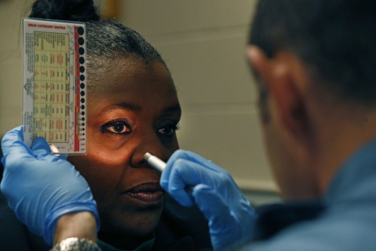 A Colorado trainer, left, evaluates the assessment skills of a state trooper using a flashlight and so-called pupilometer while simulating a roadside investigation of a potentially intoxicated driver.