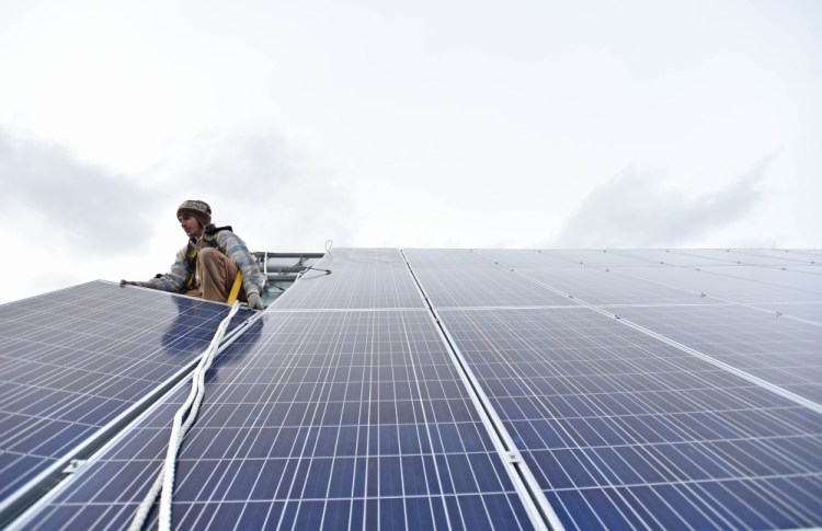 Ben Holt of InSource Renewables installs a solar panel on the Vassalboro Friends Meeting House in May.