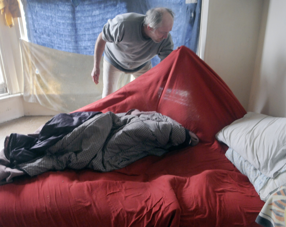 Al Sugden searches his bedding for bedbugs May 3 in his room at 382 Water St. in Augusta, where infestations have been reported in apartments and boarding houses.