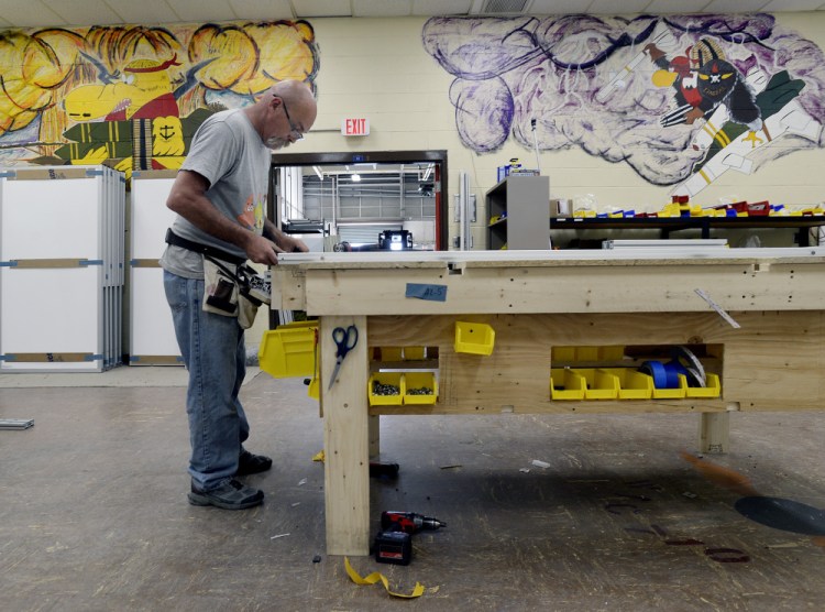 Darryl Chase of STARC Systems works on a wall module at TechPlace, an emerging business at Brunswick Landing. Co-founder Bruce Bickford says the company is on pace to triple production and "TechPlace has been a great place to be." The wall art remains from the former naval air base.