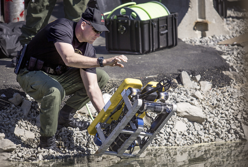 A Maine game warden launches a remote-operated device in the water off Chandlers Wharf on Thursday to help look for the body of Matthew Foster, 23, of Scarborough.