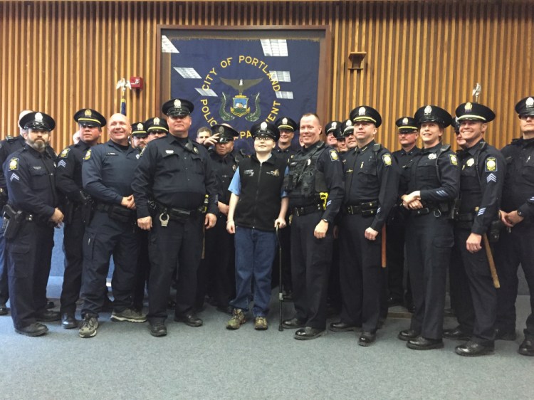 Zachary Johnson stands at the center of officers of the Portland Police Department. The teen took his badge to chemotherapy appointments.