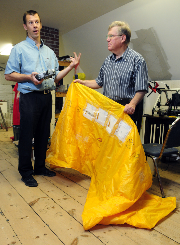 Stan Farrell, left, and his father, Bob Farrell, discuss the controllable unmanned parachute prototype they're working on at Wizbe Innovations in Manchester.