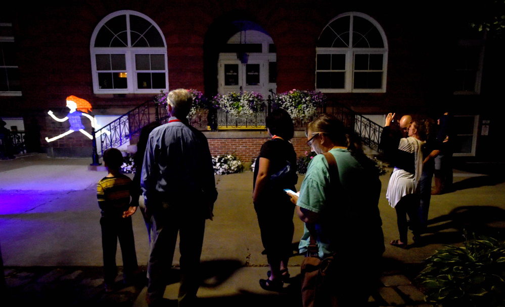 Spectators watch the projected animated creations of VJ Sauve during a performance Friday at Castonguay Square in Waterville.