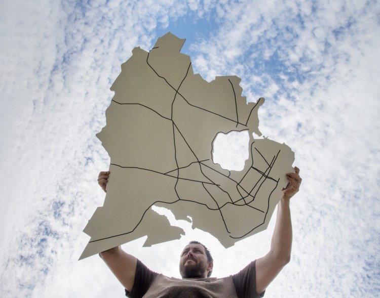 Jake Ryan of Open Bench Project holds art in the shape of Portland, jagged coastline, Back Cove and all, that will be used to help the public provide ideas for the city's master  plan.