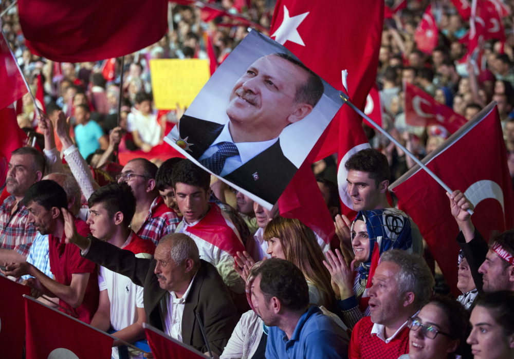 Government supporters wave Turkish flags and hold a picture of Turkish President Recep Tayyip Erdogan during a rally in Taksim Square in Istanbul on Tuesday. The Turkish government accelerated its crackdown on alleged plotters of the failed coup against Erdogan and he called the attempted putsch "a gift from God." Associated Press/Petros Giannakouris