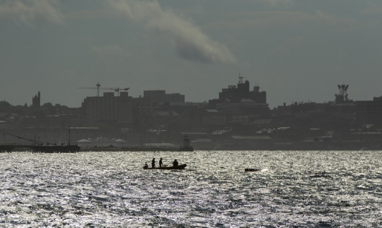 A U.S. Coast Guard rescue boat sits near a capsized sailboat in Casco Bay after four people were rescued when a strong afternoon squall swept through the region Saturday.