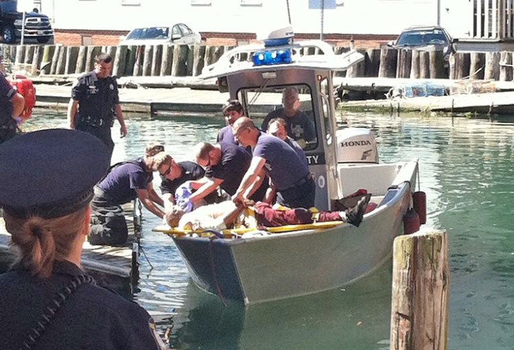 Emergency personnel with the Portland Fire Department attend to a man who fell into the water at Custom House Wharf Saturday morning. Photo by Peter McGuire/Staff Writer