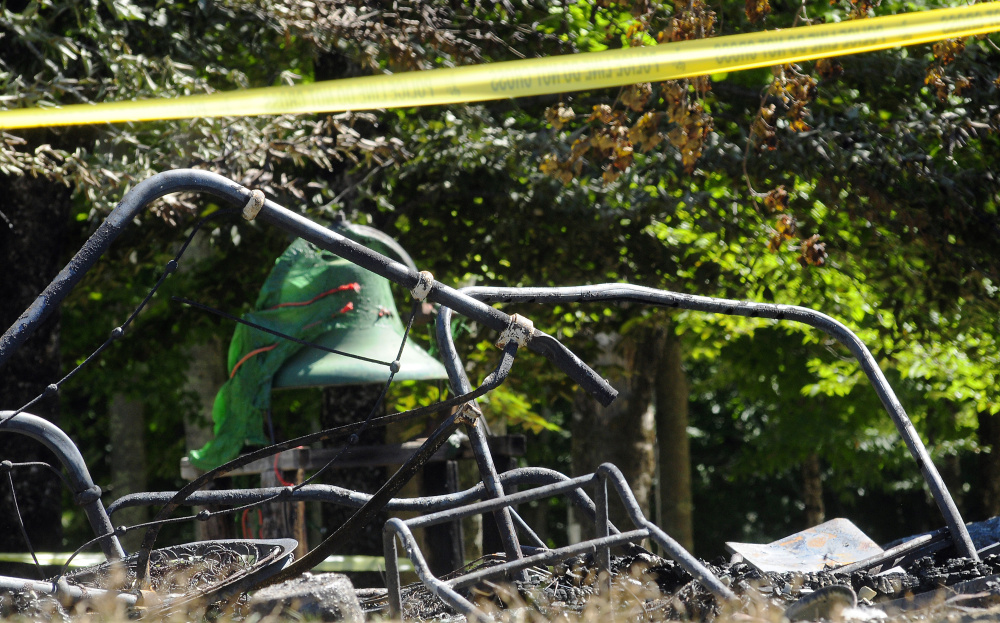 This photo taken on Tuesday shows metal bed frames from a bunkhouse in front of the dining hall's dinner bell after a fire on Monday at the Washington Advent Christian Camp in Washington.