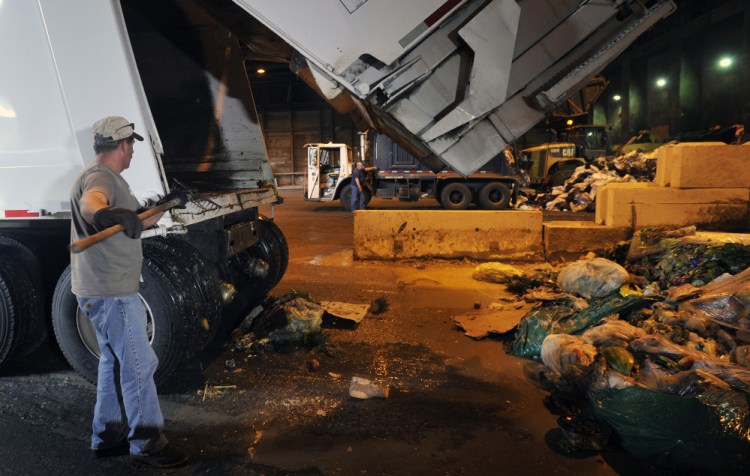 Randy Spaulding of Agri-Cycle Energy uses a rake to remove food waste from the back of a truck after it unloaded at ecomaine in Portland. The plant may handle 5,000 tons of food waste in the first year.