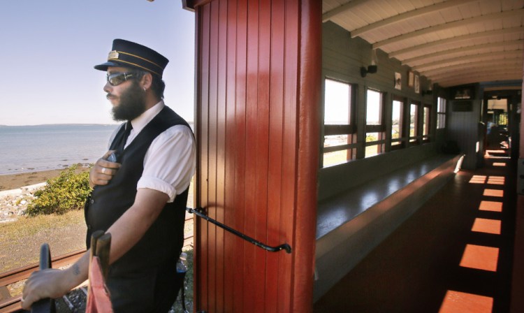 Ron Theriault keeps watch from the back of a car on the Maine Narrow Gauge Railroad as the train moves along Portland's waterfront on Monday. 
Gregory Rec/Staff Photographer