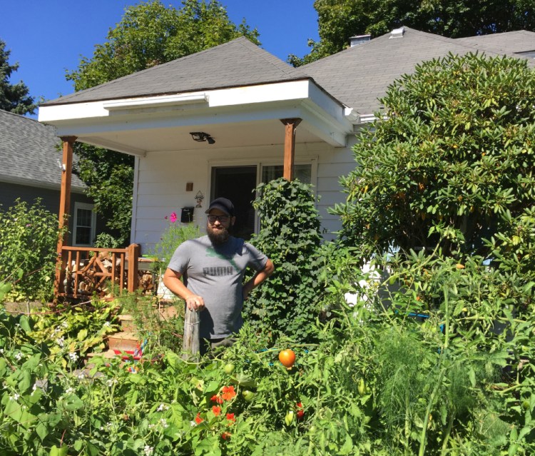 John Hychko of South Portland stands Tuesday in his front-yard garden on Barstow Street, where he and his wife, Shannon, grow a wide variety of vegetables, fruits and flowers without pesticides.