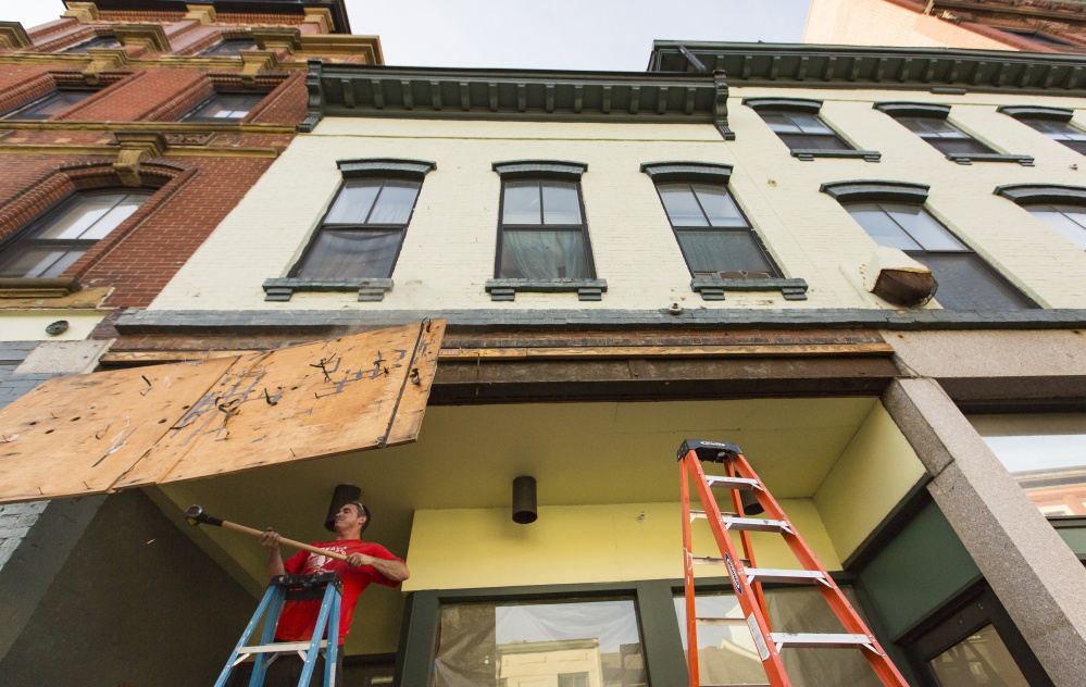 Josh Duball of Class Acts Property Management demolishes the last remnants of the old Paul’s Food Center sign on Congress Street in Portland on Tuesday. Portland Flea-for-All, an antiques and vintage goods store, is scheduled to open in the location on Thursday, according to store co-owner Erin Kiley. Kiley said Portland Flea-for-All vacated its old location at 125 Kennebec St. in Bayside in July, and she and her husband, Nathaniel Baldwin, have been working since then to get the new space ready. Ben McCanna/Staff Photographer