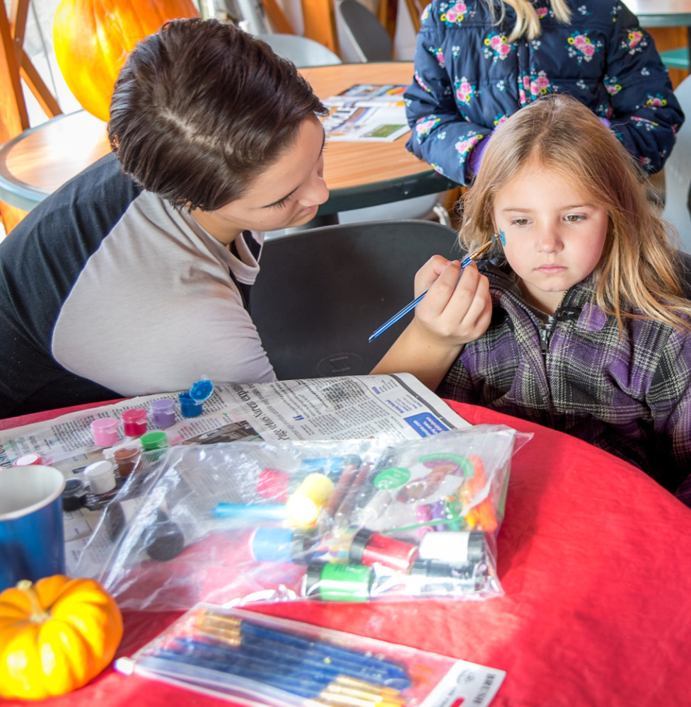 Brenna Rolfe gets a cat painted on her face Saturday by Fall Festival volunteer Cailynn Colby at the Quarry Road Trails recreation area.