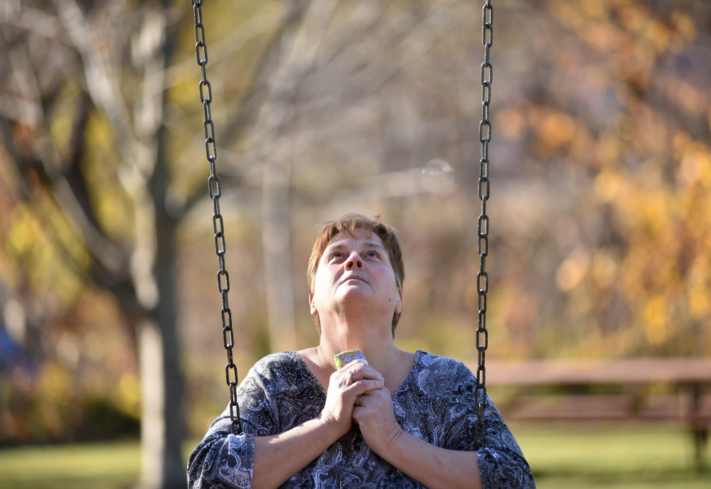  Jackie Bragg looks to the sky Friday and clutches a memorial quilt to her chest while she swings at Mill Island Park in Fairfield, where she used to take her daughters as children. The daughters, Amanda Bragg and Amy DeRosby, were shot and killed a year ago in Oakland.