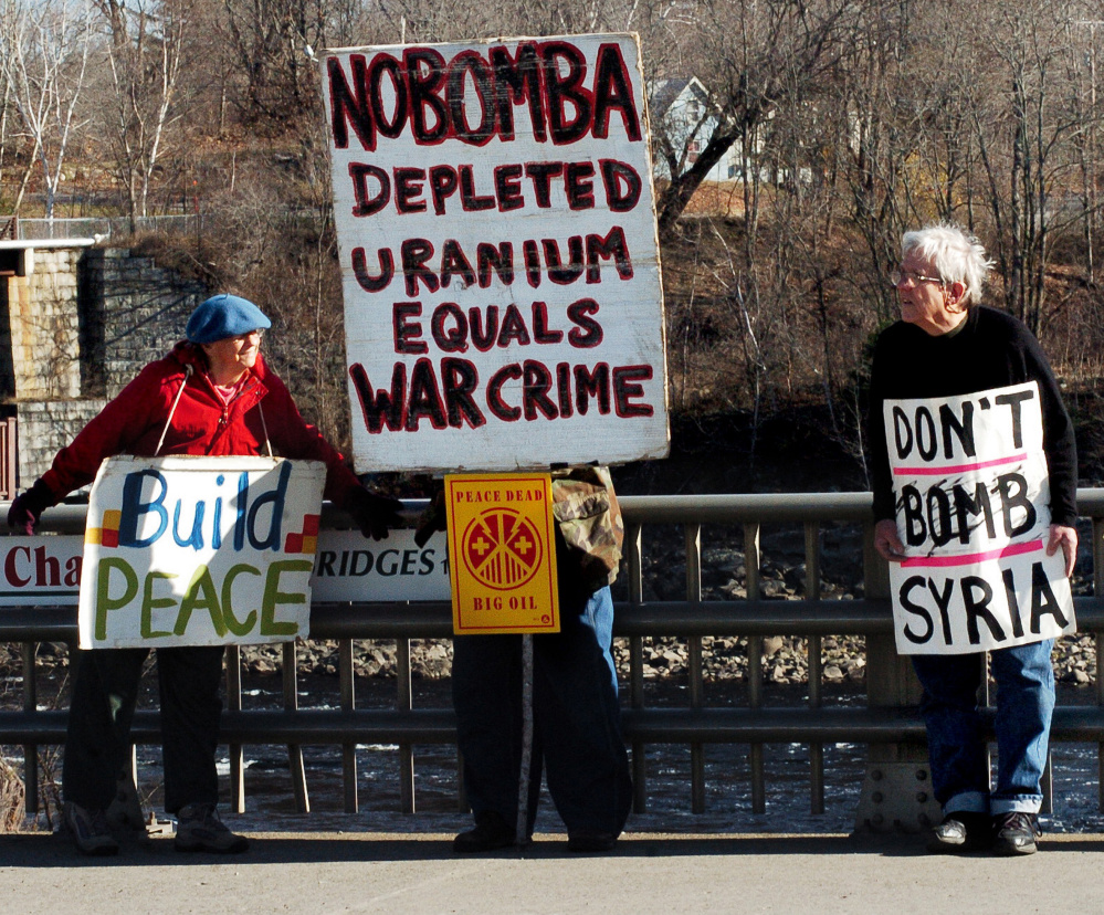 Lynne Harwood and Mark Roman make their case on a bridge in Skowhegan on Sunday. Some protesters have come there for a decade to advocate for a peaceful world. David Leaming/Morning Sentinel