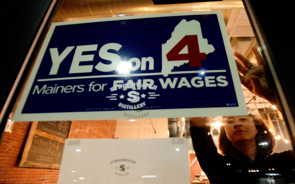 Amy Holstead, campaign manager for Yes on 4, hangs a sign at Stroudwater Distillery as she gets ready for supporters to show up and watch results Tuesday.