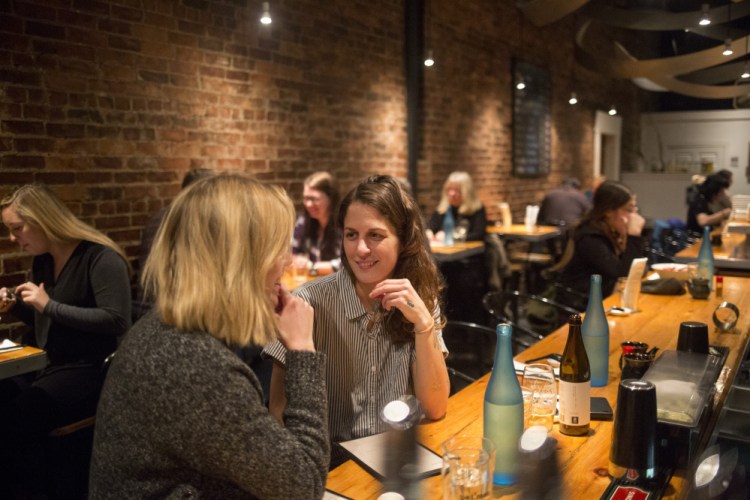 Anni Woods, left, and Sam Malone, both of Portland, chat as they wait for their meal.