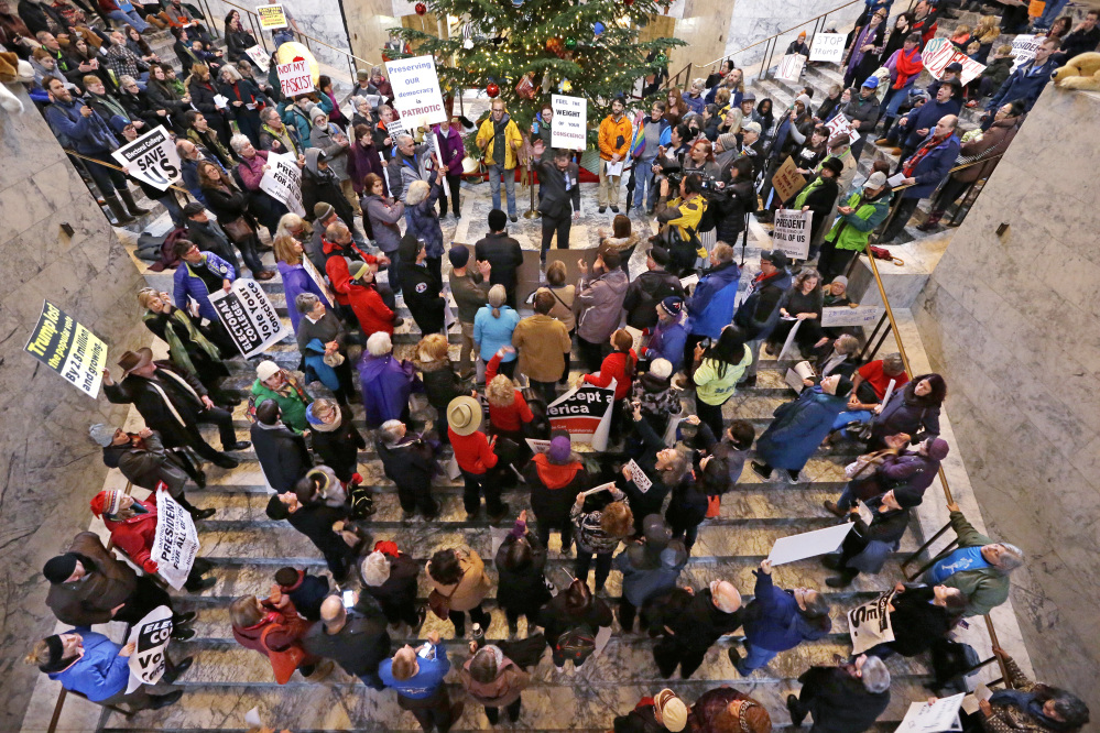 Bret Chiafalo, an elector and co-founder of the Hamilton Electors, upper center, waves after addressing a crowd protesting Electoral College voting Monday in Olympia, Wash. Chiafalo planned to vote for Republican Ohio Gov. John Kasich during Monday's Electoral College vote.