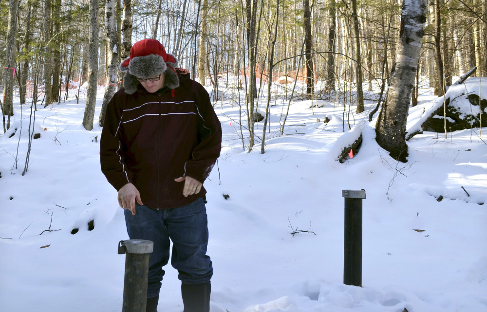 Richard Higgins, whose family's well water has been contaminated by a suspected carcinogen from a Dartmouth College dump site, looks down at one of many test wells installed to monitor the groundwater in Hanover, N.H.